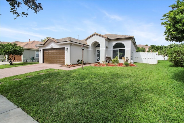 mediterranean / spanish home featuring a garage and a front yard