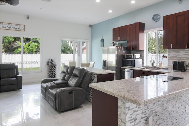 kitchen featuring stainless steel appliances, decorative backsplash, sink, light tile patterned flooring, and light stone countertops