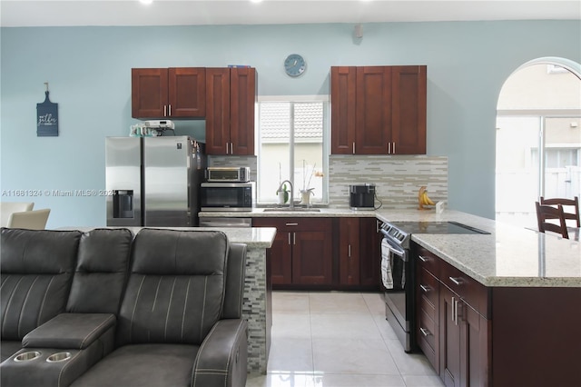 kitchen with tasteful backsplash, light tile patterned flooring, appliances with stainless steel finishes, light stone countertops, and sink