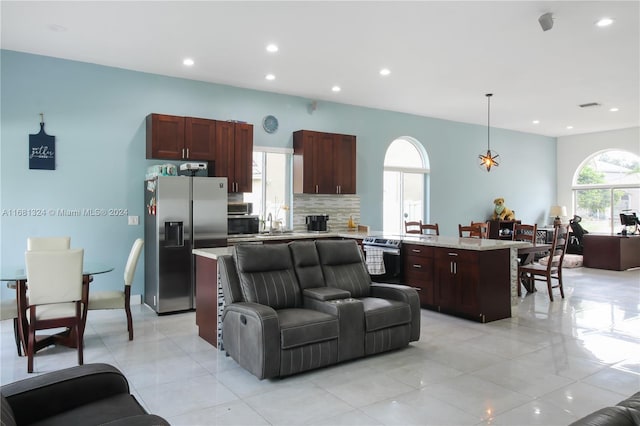 kitchen featuring stainless steel fridge, a healthy amount of sunlight, pendant lighting, and a center island