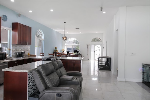 kitchen with a center island, light tile patterned flooring, backsplash, appliances with stainless steel finishes, and decorative light fixtures