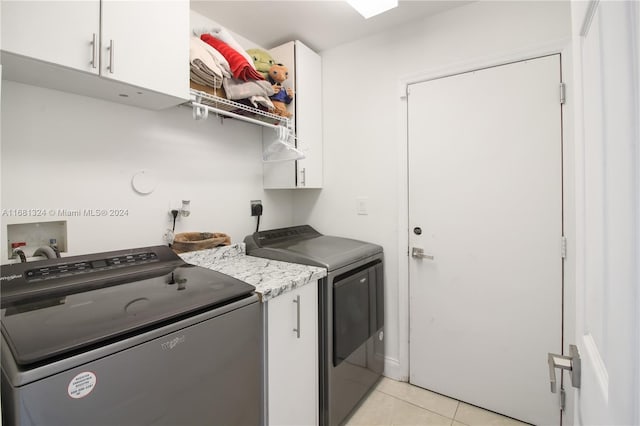 laundry room featuring washer and clothes dryer, cabinets, and light tile patterned flooring