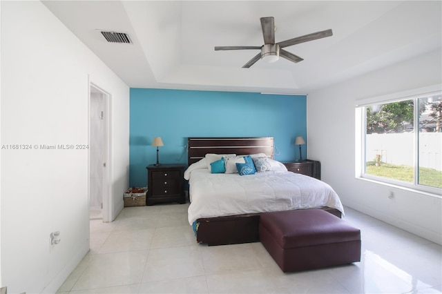 bedroom with light tile patterned floors, ceiling fan, and a raised ceiling