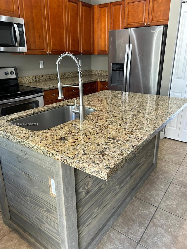 kitchen featuring light stone countertops, sink, light tile patterned flooring, a kitchen bar, and stainless steel appliances