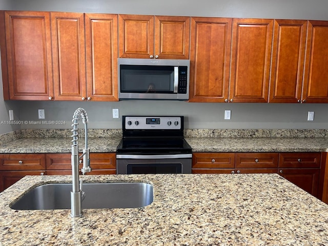 kitchen featuring stainless steel appliances, sink, and light stone counters