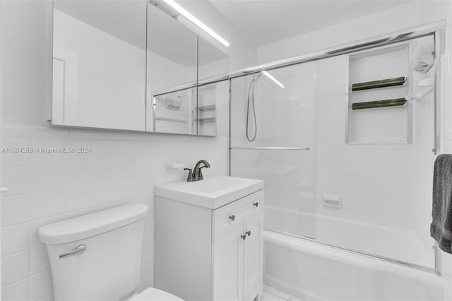 full bathroom with vanity, toilet, combined bath / shower with glass door, and tile walls