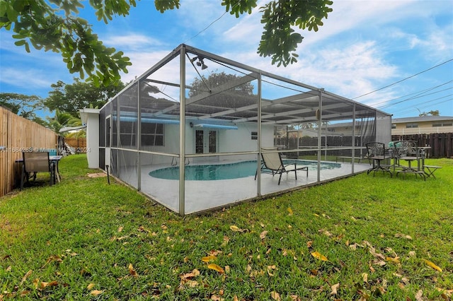 view of pool with a yard, a patio area, and glass enclosure