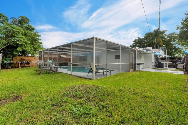 back of property with a patio, a fenced in pool, a lanai, and a lawn