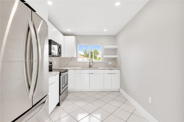 kitchen featuring decorative backsplash, light tile patterned floors, appliances with stainless steel finishes, white cabinetry, and sink