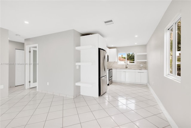 kitchen with backsplash, sink, white cabinets, light tile patterned floors, and appliances with stainless steel finishes