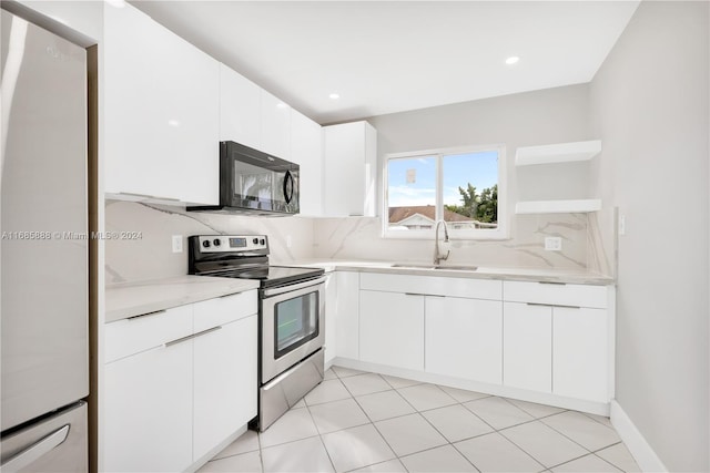 kitchen with electric range, backsplash, white cabinetry, white fridge, and sink