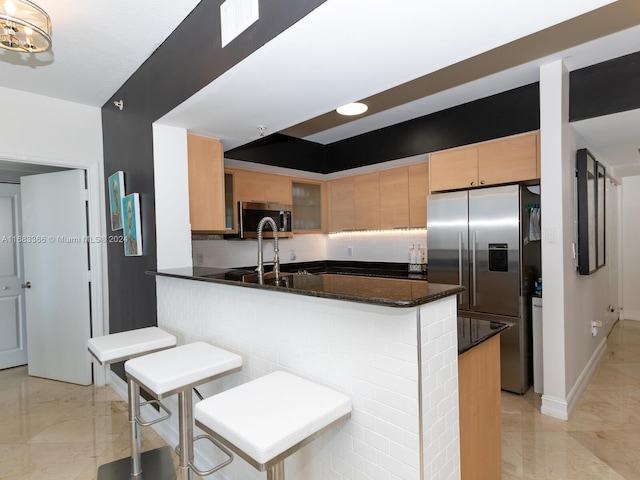 kitchen with a kitchen bar, dark stone countertops, kitchen peninsula, and stainless steel appliances