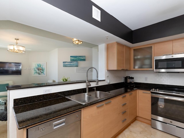 kitchen featuring kitchen peninsula, sink, dark stone counters, and appliances with stainless steel finishes