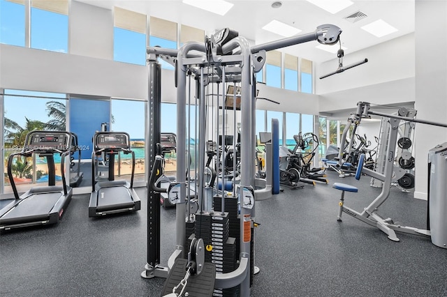 gym featuring a towering ceiling and a wealth of natural light