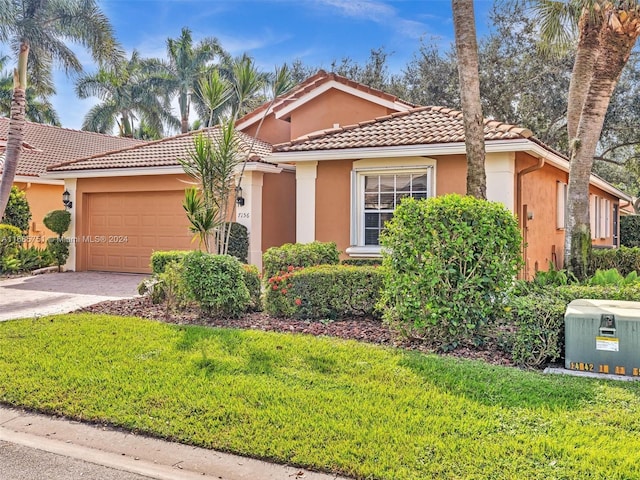 mediterranean / spanish house with stucco siding, a tile roof, an attached garage, driveway, and a front lawn