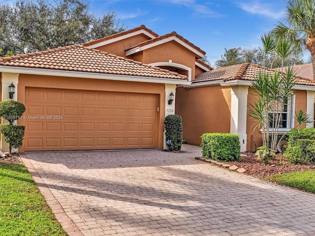 mediterranean / spanish-style home featuring decorative driveway, an attached garage, stucco siding, and a tile roof