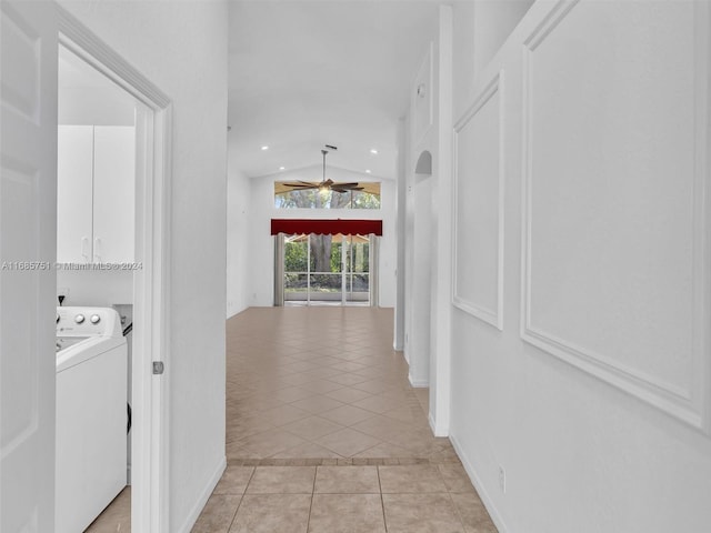 hallway with washer / dryer, light tile patterned floors, and lofted ceiling