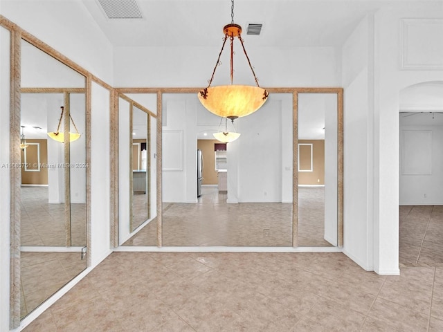 unfurnished dining area with arched walkways and tile patterned floors