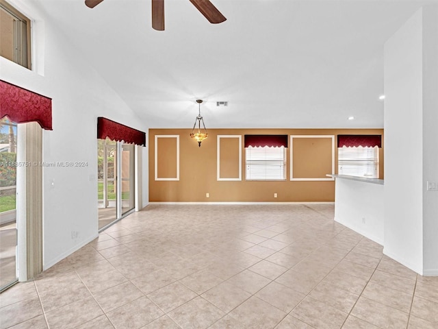 tiled spare room featuring lofted ceiling and ceiling fan with notable chandelier