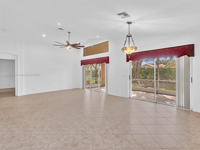 empty room with ceiling fan, a high ceiling, and light tile patterned floors