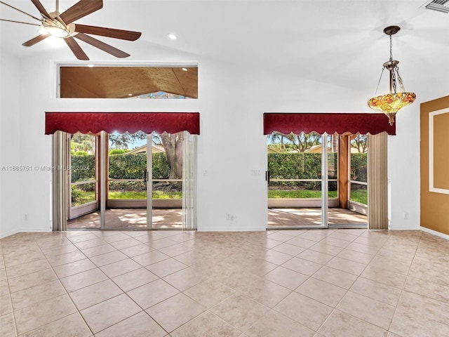 unfurnished room with high vaulted ceiling, tile patterned flooring, baseboards, healthy amount of natural light, and a ceiling fan