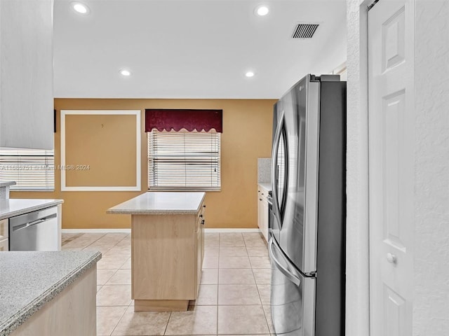 kitchen with appliances with stainless steel finishes, light brown cabinets, a center island, and light tile patterned flooring