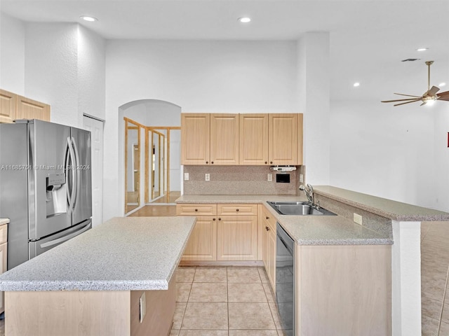 kitchen with appliances with stainless steel finishes, kitchen peninsula, sink, and light brown cabinets