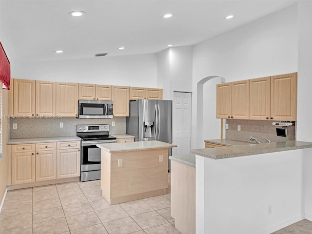 kitchen with kitchen peninsula, stainless steel appliances, light stone counters, high vaulted ceiling, and decorative backsplash