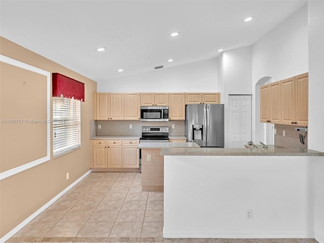 kitchen featuring appliances with stainless steel finishes, light brown cabinets, lofted ceiling, decorative backsplash, and a peninsula