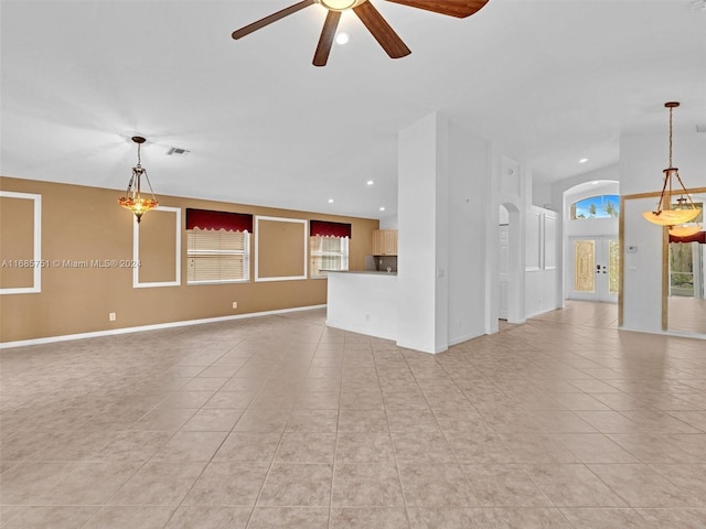 unfurnished living room featuring light tile patterned flooring and ceiling fan with notable chandelier