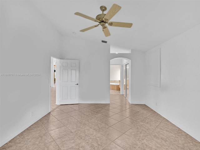 empty room featuring ceiling fan, lofted ceiling, and light tile patterned floors