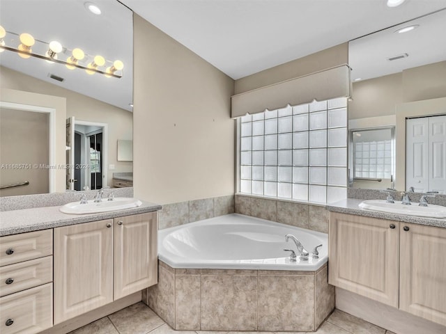 bathroom with vanity, vaulted ceiling, tiled bath, and tile patterned flooring