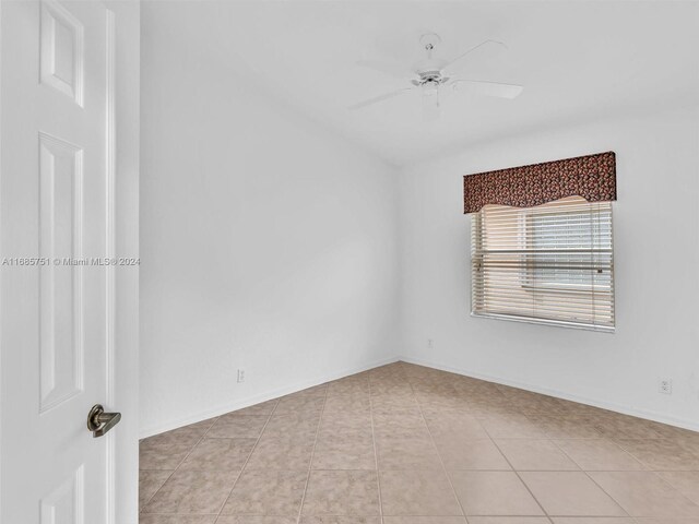 spare room with a ceiling fan, light tile patterned flooring, and baseboards