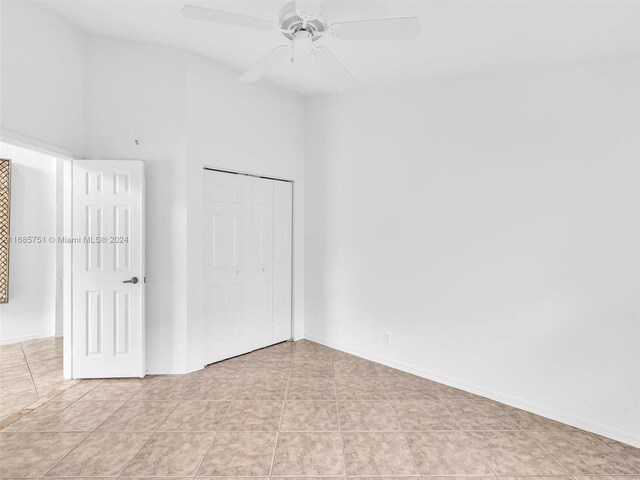 unfurnished bedroom with light tile patterned floors, a closet, ceiling fan, and baseboards
