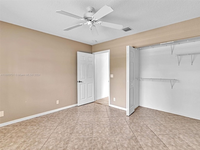 unfurnished bedroom featuring a closet, a textured ceiling, light tile patterned floors, and ceiling fan