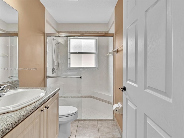 bathroom with vanity, a shower with shower door, toilet, and tile patterned floors