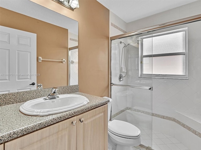 bathroom featuring vanity, a shower with shower door, and toilet