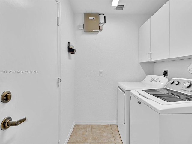 laundry area featuring light tile patterned flooring, washing machine and clothes dryer, and cabinets