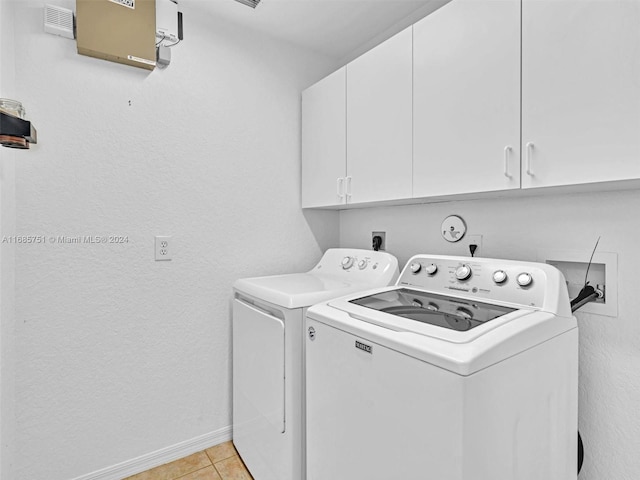 laundry area with light tile patterned flooring, cabinets, and washer and clothes dryer