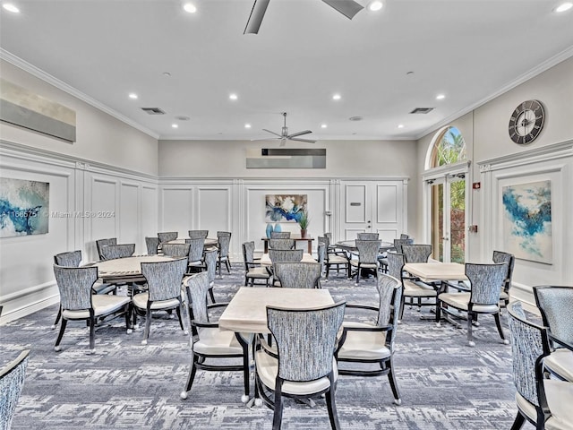 carpeted dining space with ceiling fan, a decorative wall, recessed lighting, ornamental molding, and a towering ceiling