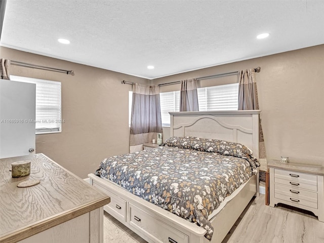 bedroom with a textured ceiling and light wood-type flooring