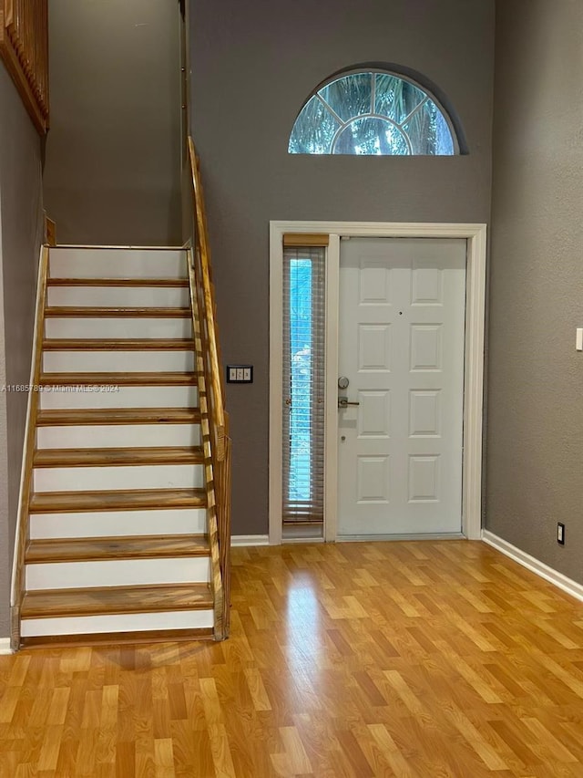 foyer entrance with a towering ceiling and light wood-type flooring