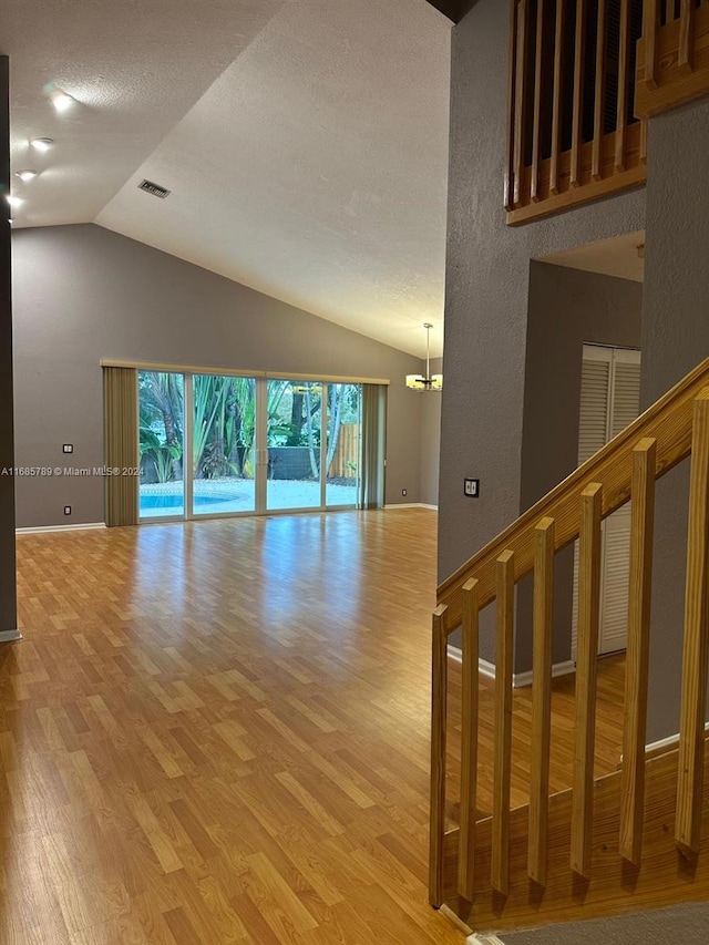 interior space featuring a chandelier, vaulted ceiling, and light wood-type flooring