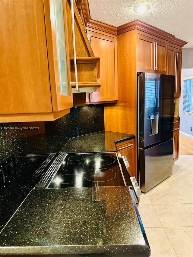 kitchen with black refrigerator with ice dispenser, a textured ceiling, stove, custom range hood, and light tile patterned flooring