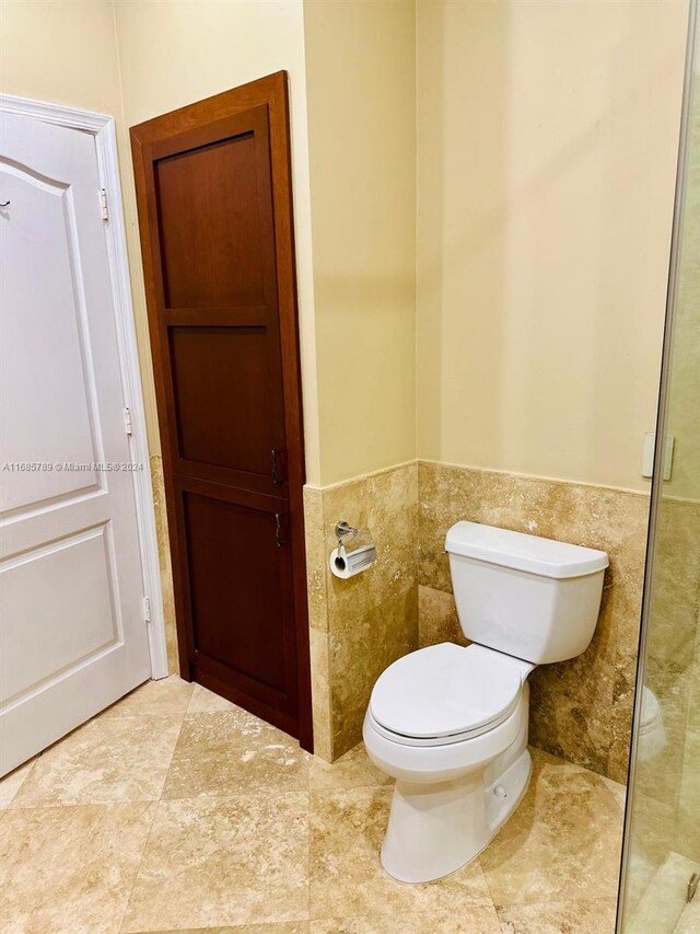 bathroom with toilet and tile walls