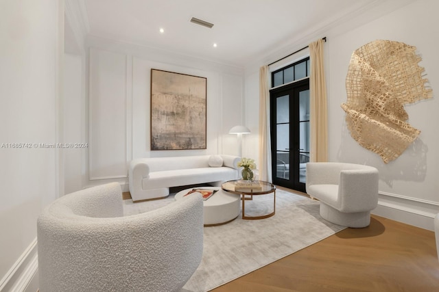 living area featuring french doors, ornamental molding, and wood-type flooring