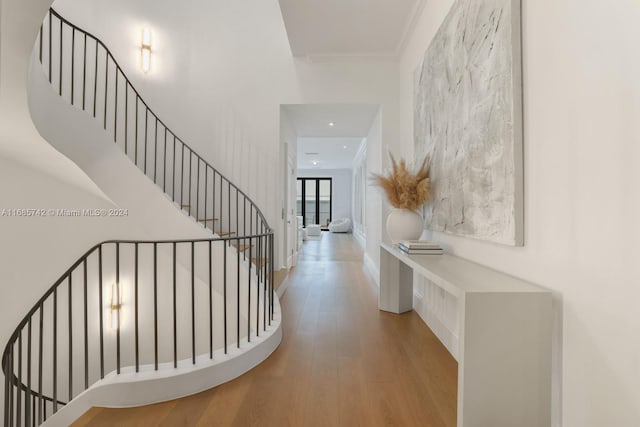 stairs with hardwood / wood-style floors and crown molding