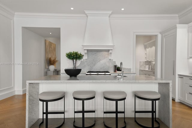 kitchen featuring a center island with sink, white cabinetry, a breakfast bar area, and tasteful backsplash