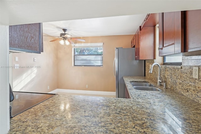 kitchen with sink, backsplash, stainless steel fridge, and light stone countertops