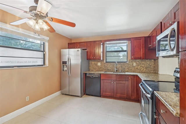 kitchen with a wealth of natural light, light stone countertops, appliances with stainless steel finishes, decorative backsplash, and sink